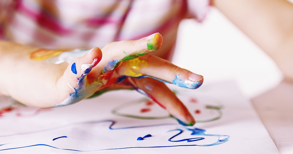 Kindergartenkind malt mit Fingerfarben