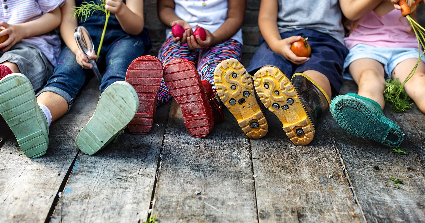 Sitzende Kinder mit bunten Gummistiefeln