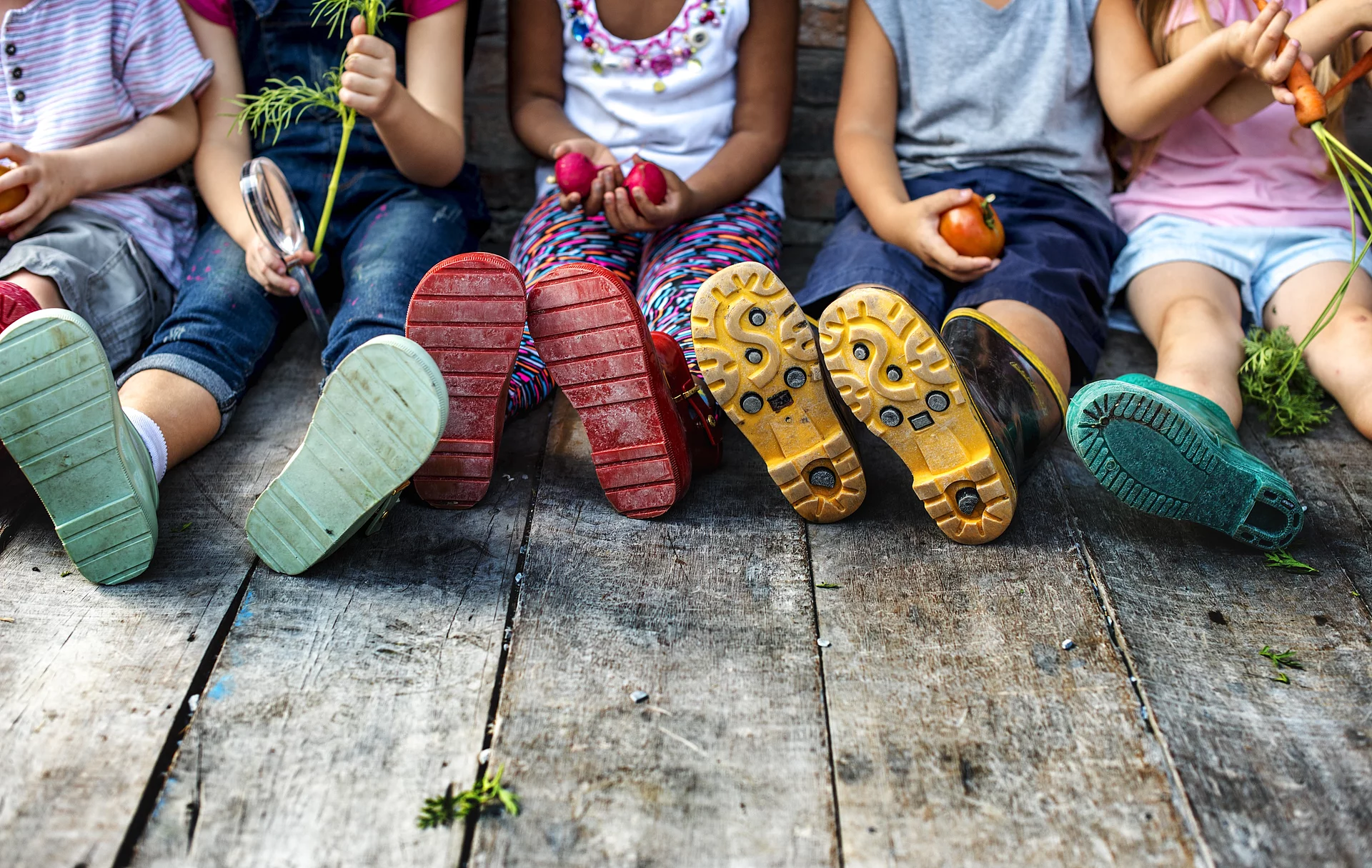 Sitzende Kinder mit bunten Gummistiefeln
